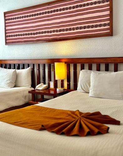 a hotel room with two beds and a lamp at Hotel Nututun Palenque in Palenque