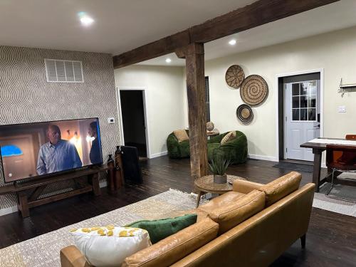 a living room with a couch and a flat screen tv at Historic Carriage House Near Attractions in Saint Louis