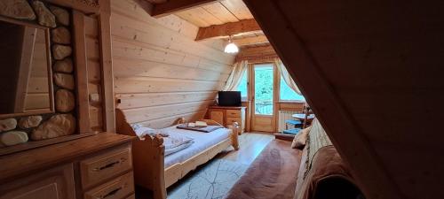 a bedroom in a log cabin with a bed and a television at Pokój z balkonem 5 in Kościelisko