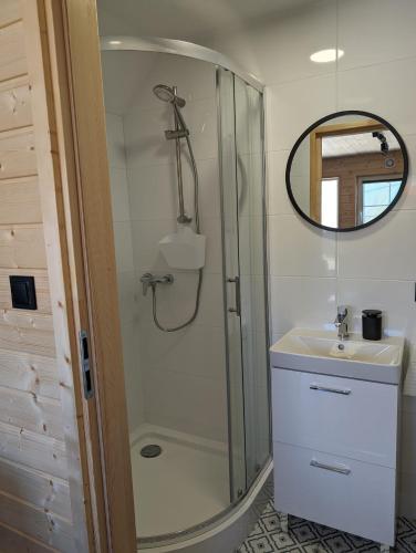 a bathroom with a shower and a sink and a mirror at Domki Słodka Magnolia in Karwia