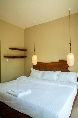 a bedroom with a white bed with two pendant lights at Krazy Gecko Resort in Pokhara