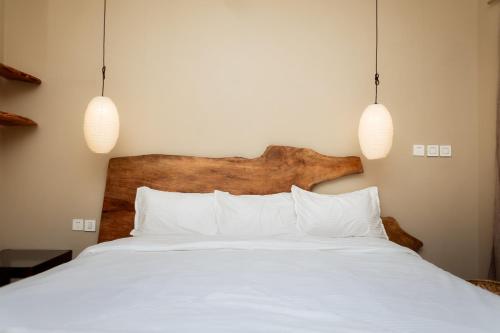 a bedroom with a white bed with two pendant lights at Krazy Gecko Resort in Pokhara
