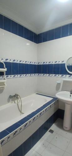 a blue and white bathroom with a tub and a sink at Sidi mahrsi Nabeul in Nabeul