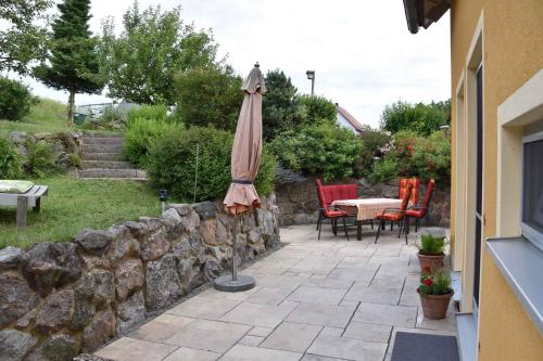 an umbrella sitting on a patio next to a stone wall at Holiday home in Pfreimd - Oberpfalz 38096 in Pfreimd