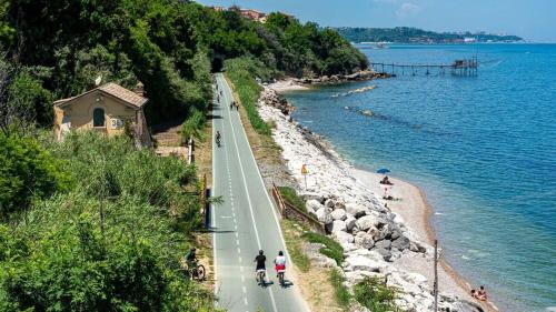a road next to the water with people on bikes at Terrazza Dante in San Vito Chietino