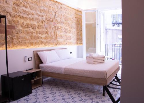 a bedroom with a bed and a brick wall at San Carlo Cuore di Palermo in Palermo