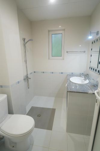 a white bathroom with a toilet and a sink at Hotel Avis in Sandanski