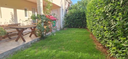 a backyard with a wooden table and a green hedge at Villa Oaza Verde in Herceg-Novi