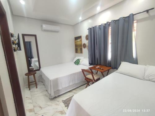 a hotel room with two beds and a table at POUSADA NOSSO CANTO ALTER in Alter do Chao