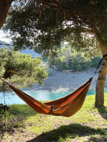a hammock hanging from a tree next to a river at Hôtel l'Équipe in Le Sauze