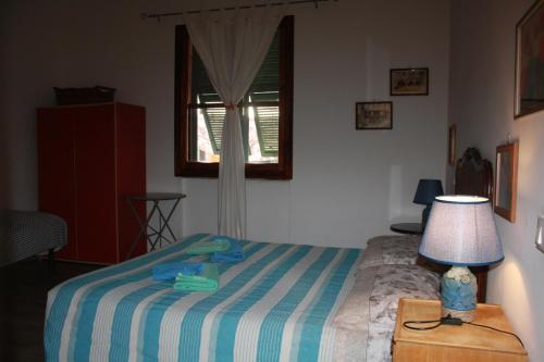 a bedroom with a bed with a lamp and a window at La Quercia Agriturismo in Imperia