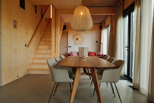 a dining room with a wooden table and chairs at NIEUW Eco design bosvilla met sauna en xl tuin in Wateren