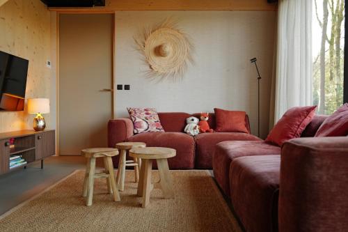 a living room with a red couch and two tables at NIEUW Eco design bosvilla met sauna en xl tuin in Wateren
