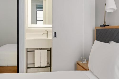 a bathroom with a sink and a bed with a mirror at Newly Renovated Rooms at Club Quarters Hotel Times Square, New York in New York