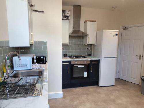 a kitchen with a white refrigerator and a sink at En-Suite Double-Bedroom in the Heart of Salford Manchester CR2 Perfect for Short Stays in Manchester