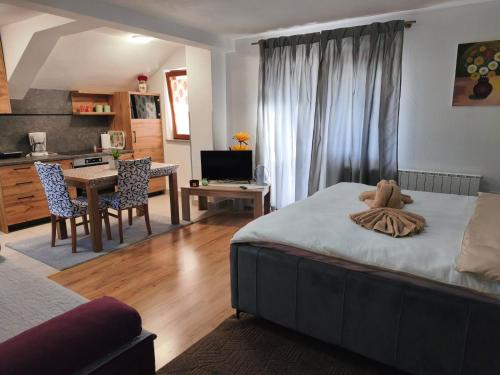 a bedroom with a bed and a kitchen with a table at Apartments & Rooms Ramljak in Korenica