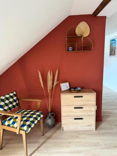 a chair and a dresser in a room with a red wall at Les Rives du Château 2 - Vue sur les bateaux in Saverne