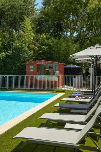 a row of lounge chairs and an umbrella next to a pool at Mercure Aix en Provence Beaumanoir in Aix-en-Provence