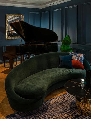 a green couch in a living room with a piano at The Wallace Hotel in New York