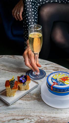 a person holding a glass of wine next to a table with food at The Wallace Hotel in New York