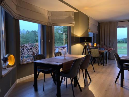 a dining room with a table and chairs and a large window at Dworek Pod Wierzbami 