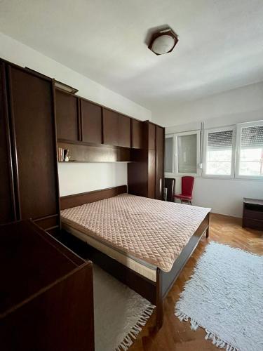 a bedroom with a large bed and a red chair at Tivat Centar Apartment in Tivat