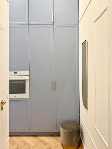 a kitchen with white cabinets and a stool at ROOSEVELTA RESIDENCE Apartments - przy OFF Piotrkowska in Łódź