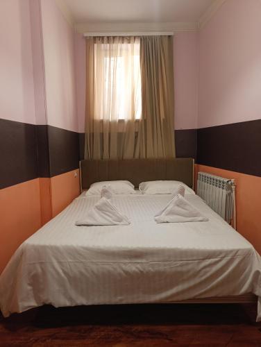 Un dormitorio con una cama con sábanas blancas y una ventana. en Dreamer's Den Hostel and Tours, en Ereván