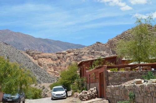 two cars parked next to a house in the mountains at El Quitapenas Tilcara in Tilcara