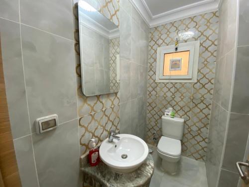 a bathroom with a white toilet and a sink at لؤلؤة داون تاون العلمين in El Alamein
