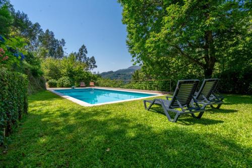 two lawn chairs sitting next to a swimming pool at Casa Azevinho - Caniçada Gêres in Soengas