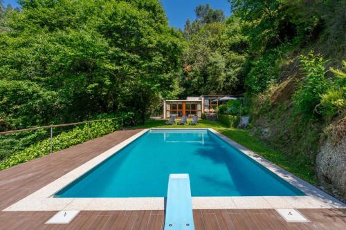 a swimming pool with a wooden deck and a house at Casa Azevinho - Caniçada Gêres in Soengas