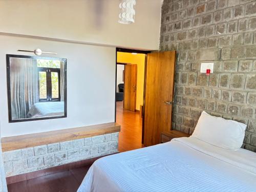 a bedroom with a bed and a brick wall at Zeenath Taj Gardens in Yelagiri