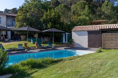 a swimming pool with chairs and umbrellas in a yard at La Tiny du Luberon in Pertuis