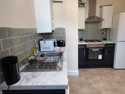 a kitchen with a sink and a dish drying rack at En-Suite Double-Bedroom in the Heart of Salford Manchester CR3 Perfect for Short Stays in Manchester
