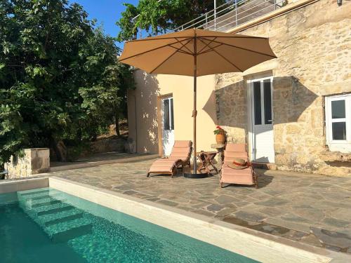 a patio with an umbrella and chairs and a pool at Le Havre in Païdhokhórion