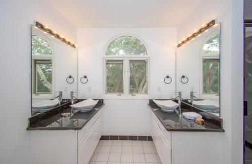 a white bathroom with two sinks and two mirrors at 702 Whiting Rd in Fripp Island