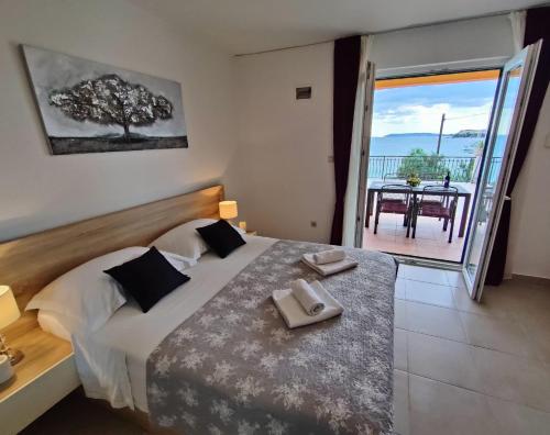 a bedroom with a bed and a balcony with a table at VILLA JURAS in Podstrana