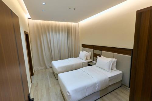 two beds in a hotel room with white pillows at شقق منازل بلقيس للشقق المخدومة الآثير in Hail