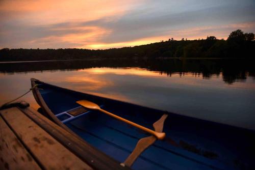 a blue boat on a lake at sunset at The Water’s Edge * * Unique Muskoka Treehouse * * in Windermere