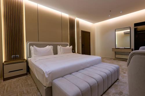 a bedroom with a large white bed and a mirror at شقق منازل بلقيس للشقق المخدومة الآثير in Hail