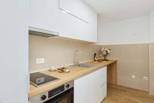 a kitchen with white cabinets and a sink at Berge Apartments in Kotor