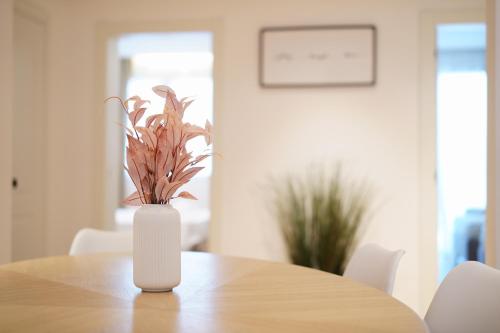 a white vase with a plant sitting on a table at La Marina Case Vacanze in Augusta