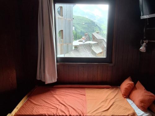un lit dans une chambre avec une grande fenêtre dans l'établissement Appartement cosy à Avoriaz - Village des Dromonts - 3 pers, 22m² - Proche centre et pistes - FR-1-633-40, à Morzine
