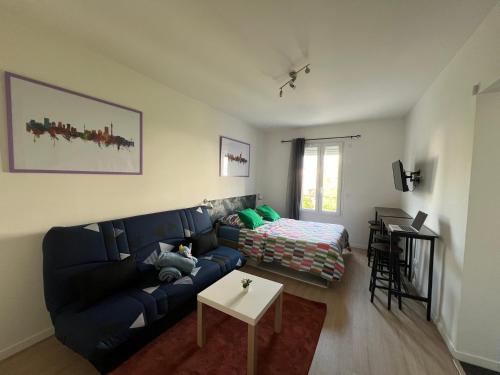 a living room with a blue couch and a table at Studio Jozy I confort et jardin en ville 4pers I Futuroscope in Châtellerault