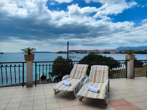 two chairs sitting on a patio overlooking the water at VILLA JURAS in Podstrana