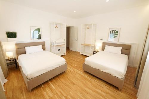 two beds in a room with white walls and wood floors at La Marina Case Vacanze in Augusta