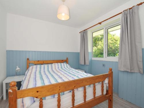 a bedroom with a wooden bed and a window at 4 Rosecraddoc Lodge Holiday Bungalows in Liskeard