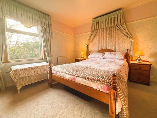 ein Schlafzimmer mit Himmelbett und Fenster in der Unterkunft Charming Lilac Cottage, Aldbrough, East Yorkshire in Aldbrough