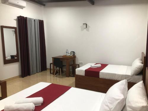 a hotel room with two beds and a desk at Kandy Home Stay in Kandy